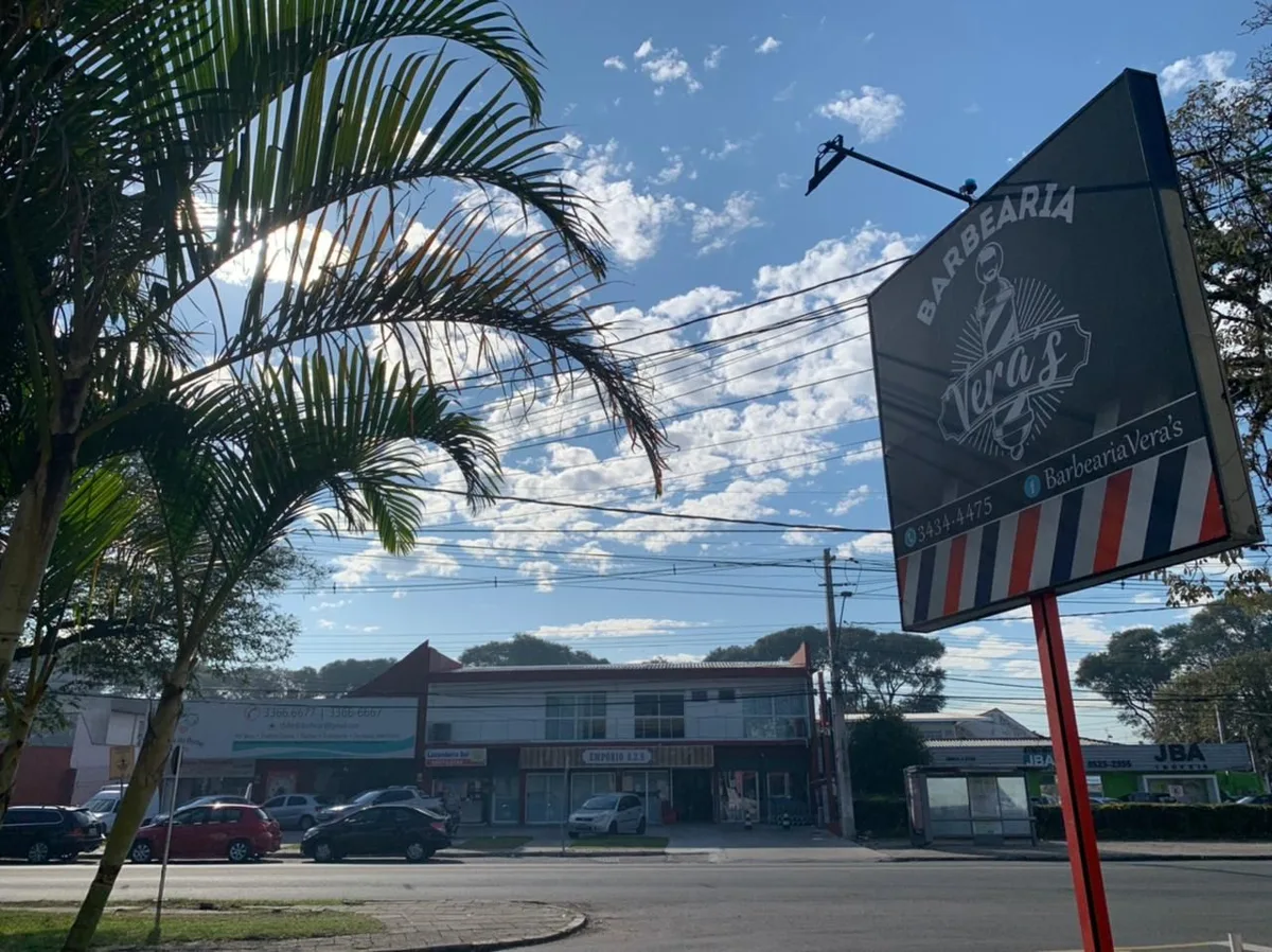 Fachada da Barbearia Vera's, no Jardim das Américas, com a placa e o poste de barbeiro na calçada